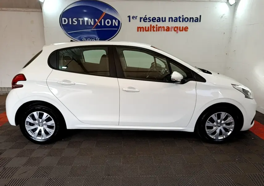 Profil côté droit d'une Peugeot 208 blanche Puretech 82 S&S ACTIVE BUSINESS, en intérieur sur sol damier noir et rouge.