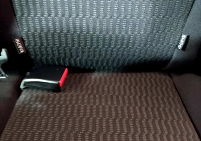 Détail de la banquette arrière noire avec étiquette ISOFIX et boucle de ceinture rouge visible sur une Peugeot 208.