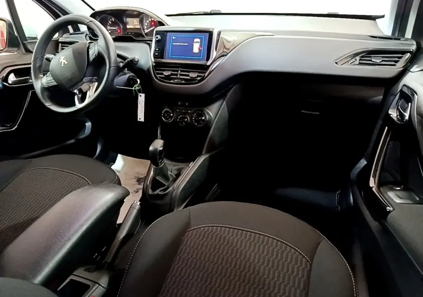 Vue intérieure avant droite de la Peugeot 208 blanche, tableau de bord avec écran tactile et volant multifonction.