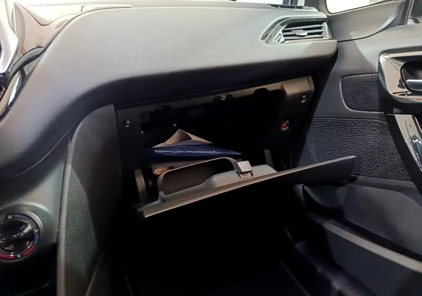 Vue intérieure côté passager de la Peugeot 208 blanche de 2018 avec boîte à gants ouverte et tableau de bord noir.