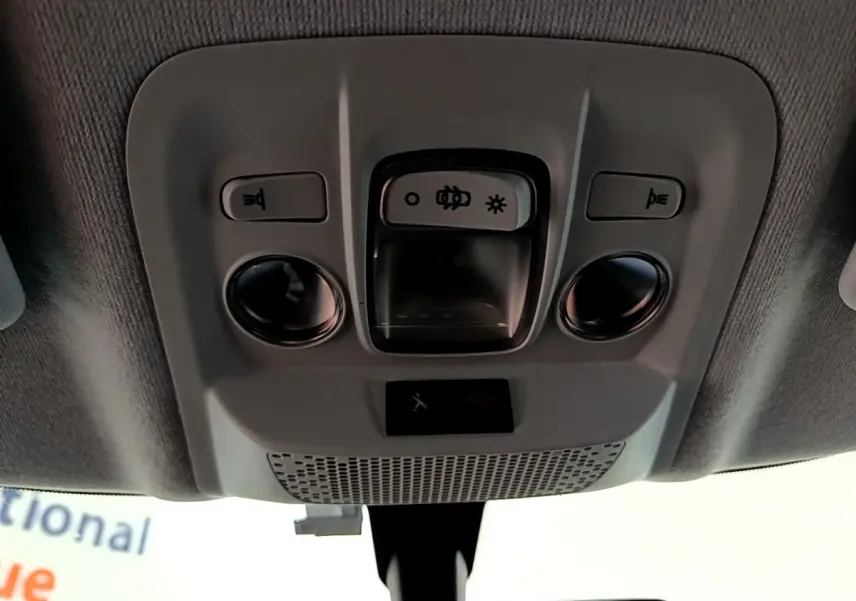 Vue intérieure du plafonnier gris avec commandes d’éclairage et boutons SOS d’une Peugeot 208 blanche 2018.