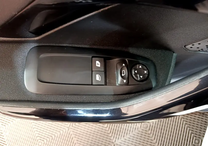 Gros plan sur les commandes de réglage des rétroviseurs et des vitres côté conducteur d’une Peugeot 208 blanche.