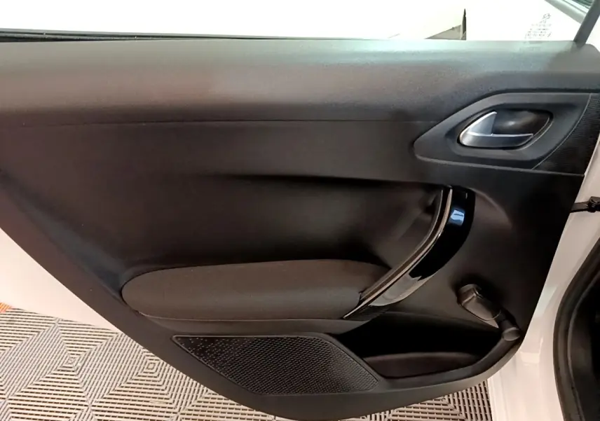 Vue intérieure de la porte avant droite noire avec poignée chromée d'une Peugeot 208 blanche de 2018.
