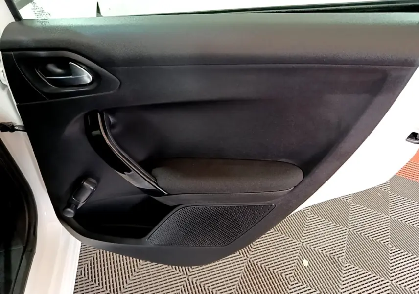 Vue rapprochée de la porte avant gauche noire d’une Peugeot 208 blanche, avec poignée et commande de vitre manuelle.