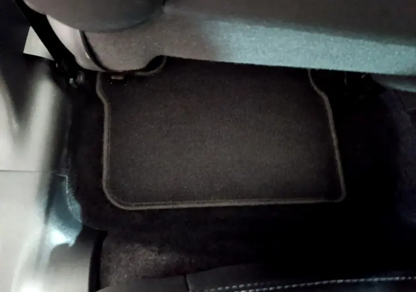 Vue rapprochée du tapis de sol noir sous le siège arrière d’une Peugeot 208 blanche de 2018.