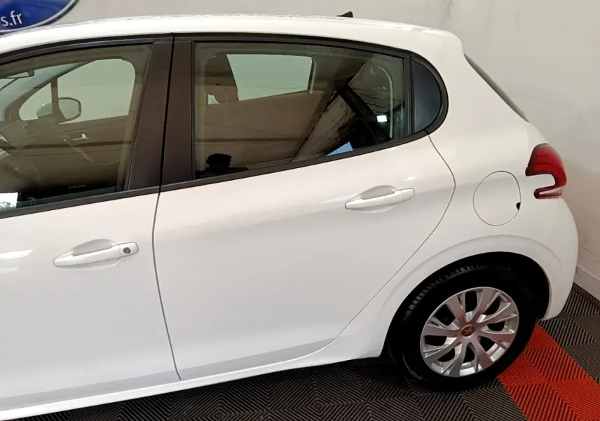 Vue latérale côté droit d'une Peugeot 208 blanche, mettant en valeur la portière arrière et la roue arrière.