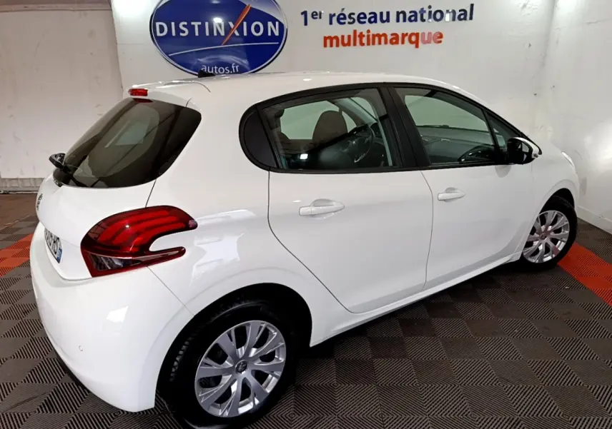 Vue 3/4 arrière droite d'une Peugeot 208 blanche Puretech 82 S&S Active Business en intérieur showroom.