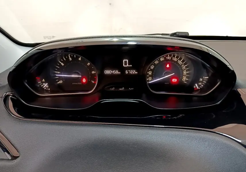 Vue rapprochée du tableau de bord numérique de la Peugeot 208 blanc, affichant le compteur et les voyants allumés.