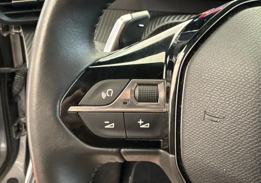 Gros plan sur les commandes gauche du volant cuir noir du Peugeot 2008 gris clair, version PureTech 130 S&S EAT8 Allure 2023.