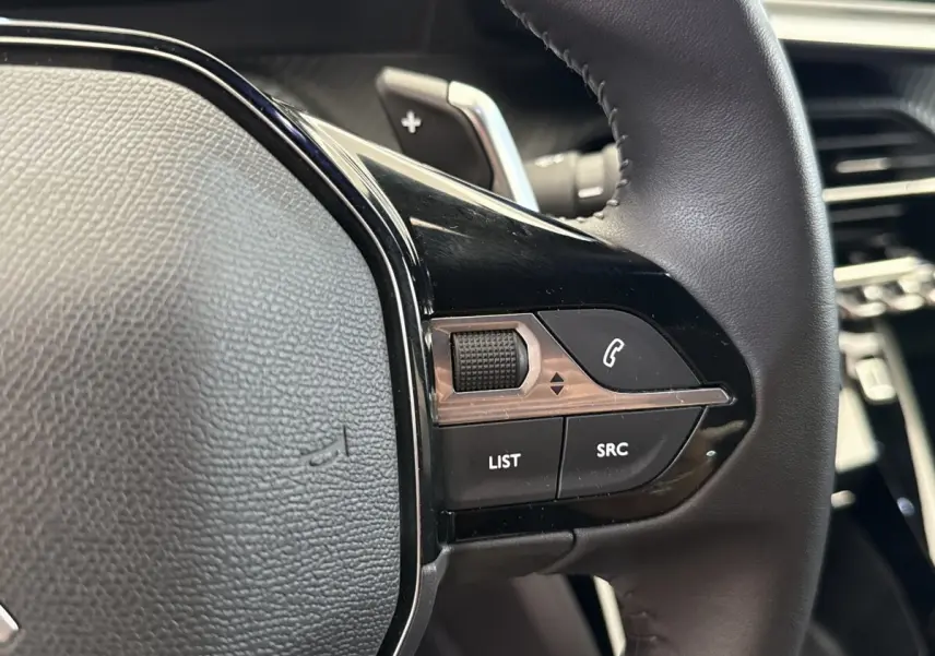 Gros plan sur les commandes multifonctions du volant cuir noir du Peugeot 2008 gris clair, version 2023.