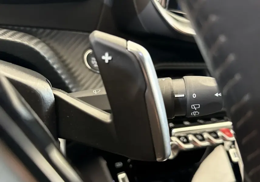 Gros plan sur la palette de changement de vitesse droite en plastique noir et chrome dans le Peugeot 2008 gris clair 2023.