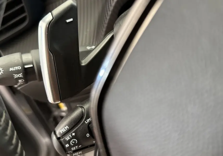 Détail du volant cuir de la Peugeot 2008 gris clair, avec commandes de régulateur de vitesse et leviers multifonctions.