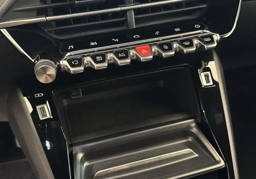 Vue rapprochée de la console centrale noire du Peugeot 2008 avec boutons chromés et ports USB visibles.