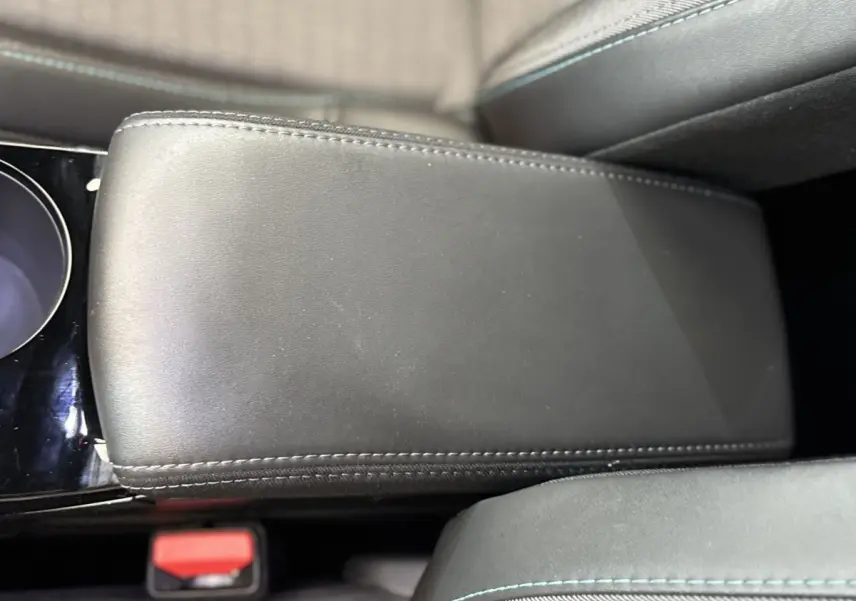 Gros plan sur l'accoudoir central en cuir noir avec surpiqûres bleues dans l'habitacle du Peugeot 2008 gris clair.