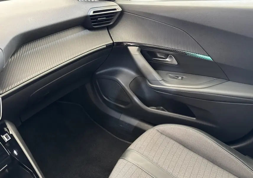 Intérieur côté passager du Peugeot 2008 gris clair, avec tableau de bord texturé et siège tissu gris.