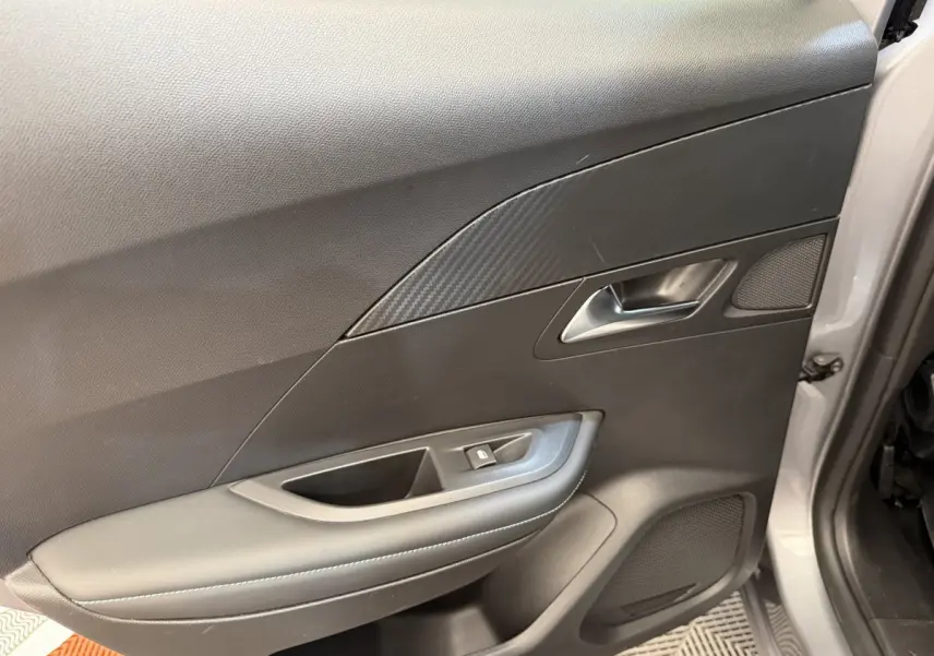 Vue rapprochée de la porte avant gauche gris clair du Peugeot 2008 avec habillage noir et insert effet carbone.