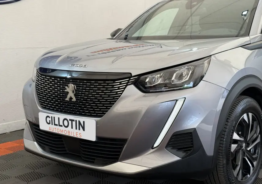 Vue 3/4 avant droit d’un Peugeot 2008 gris clair avec calandre noire et feux LED distinctifs.