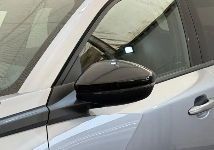 Vue rapprochée du rétroviseur noir sur la porte côté conducteur d’un Peugeot 2008 gris clair 2023.