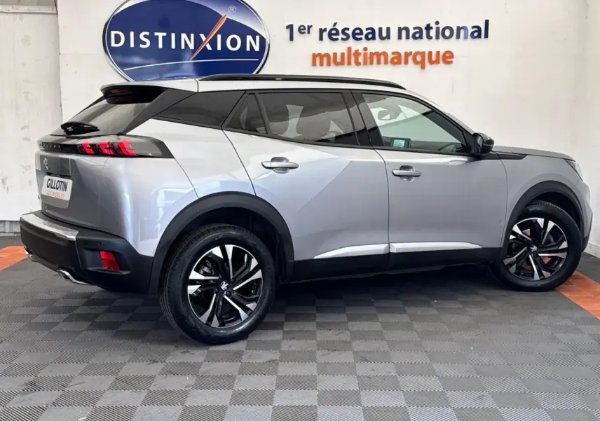 Vue profil droit d'un Peugeot 2008 gris clair 2023 avec toit noir et jantes alliage bicolores.