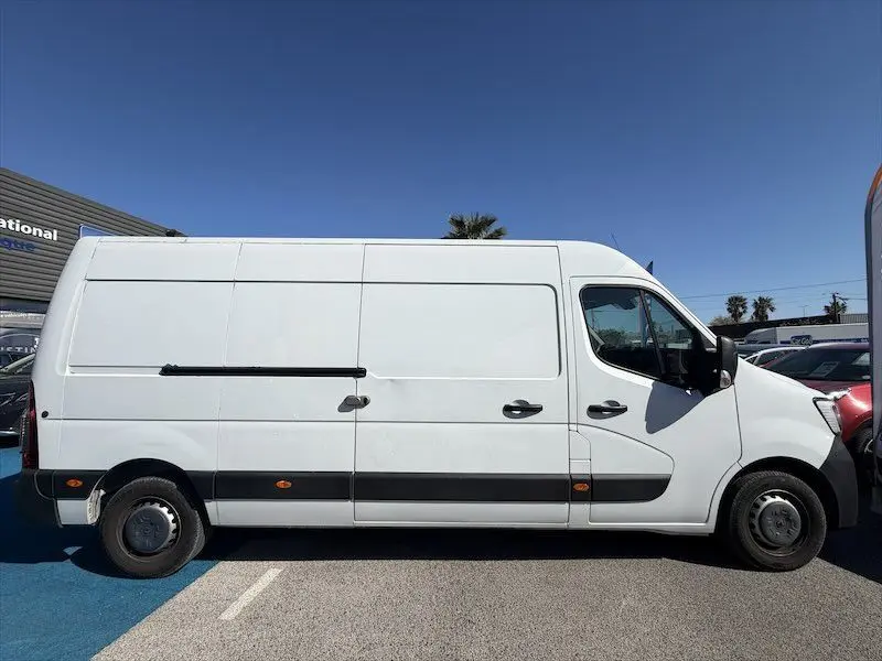 Vue de profil droit d’un utilitaire Renault Master blanc stationné en extérieur, avec porte latérale coulissante fermée.