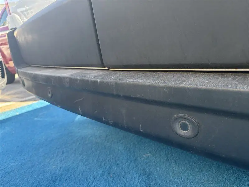 Gros plan sur le pare-chocs arrière noir du Renault Master blanc, montrant un capteur de recul circulaire.