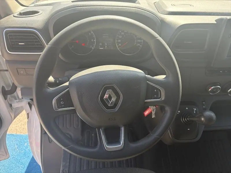 Vue intérieure centrée sur le volant noir avec logo Renault du Master blanc, tableau de bord et levier de vitesses visibles.