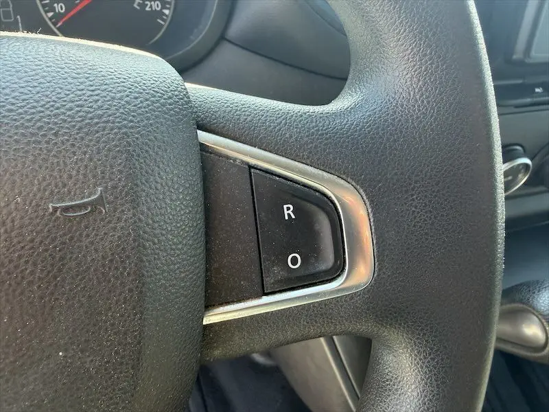 Gros plan sur les boutons R et O sur le volant noir du Renault Master blanc, vue intérieure côté conducteur.