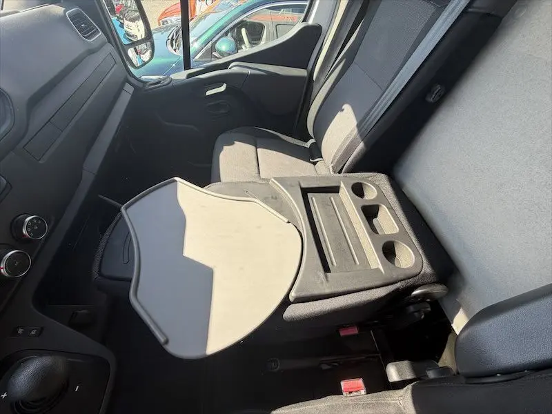 Intérieur du Renault Master blanc vu côté passager, avec tablette rabattable et sièges gris.
