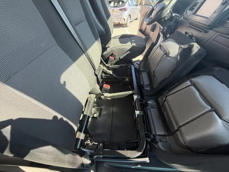 Vue intérieure côté conducteur du Renault Master blanc 2021, montrant les sièges avant et un espace de rangement sous le siège passager.
