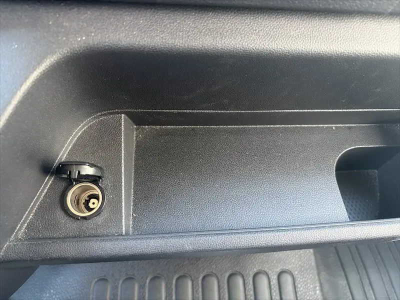Gros plan sur la prise allume-cigare noire à l'intérieur du Renault Master blanc, côté passager.