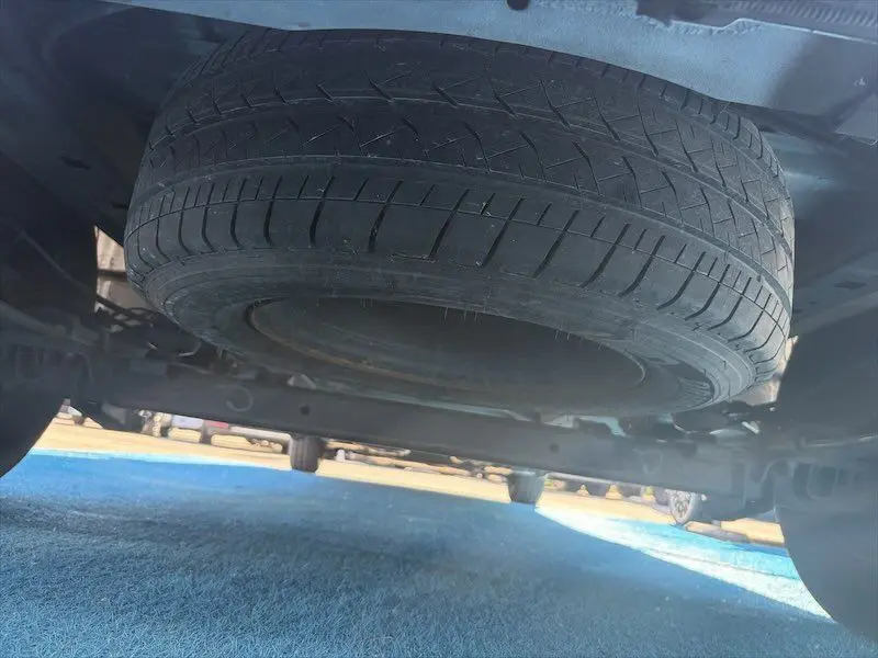 Vue en contre-plongée sous un Renault Master blanc, montrant la roue de secours fixée sous le châssis arrière.