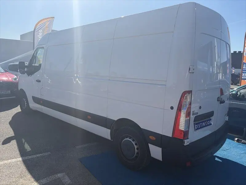 Renault Master blanc en vue 3/4 arrière droit, fourgon utilitaire avec panneaux latéraux lisses et feux arrière verticaux.