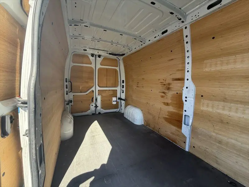 Intérieur du Renault Master blanc vu de l'arrière, montrant la zone de chargement avec parois en bois et sol noir.