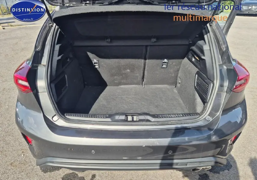 Coffre ouvert vu de l'arrière d'une Ford Focus gris magnétique 2024 avec feux arrière LED et double sortie d'échappement.