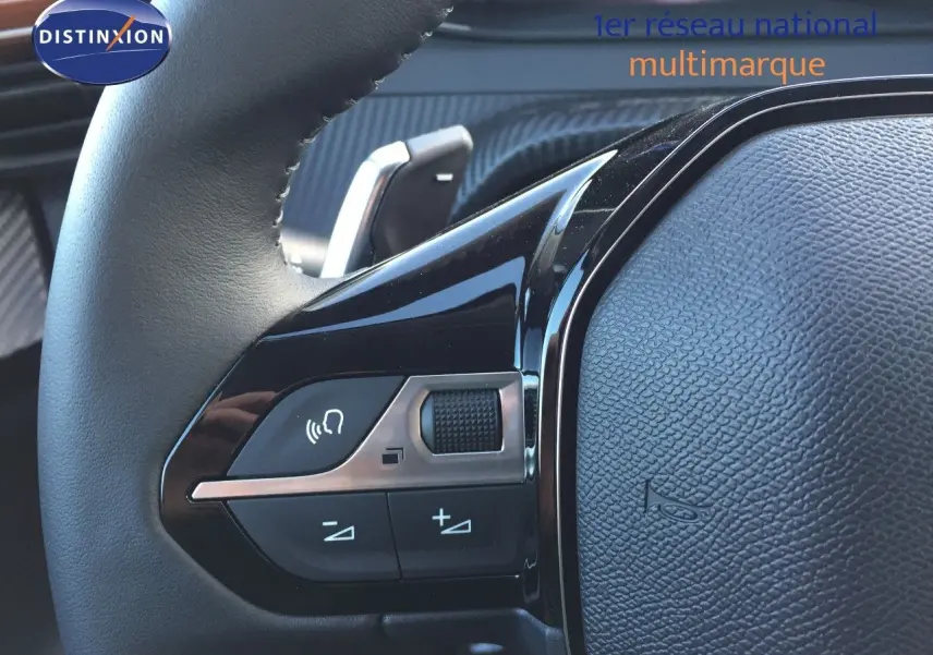 Gros plan sur les commandes du volant d'une Peugeot 208 gris selenium, mettant en valeur les boutons de volume et de téléphone.