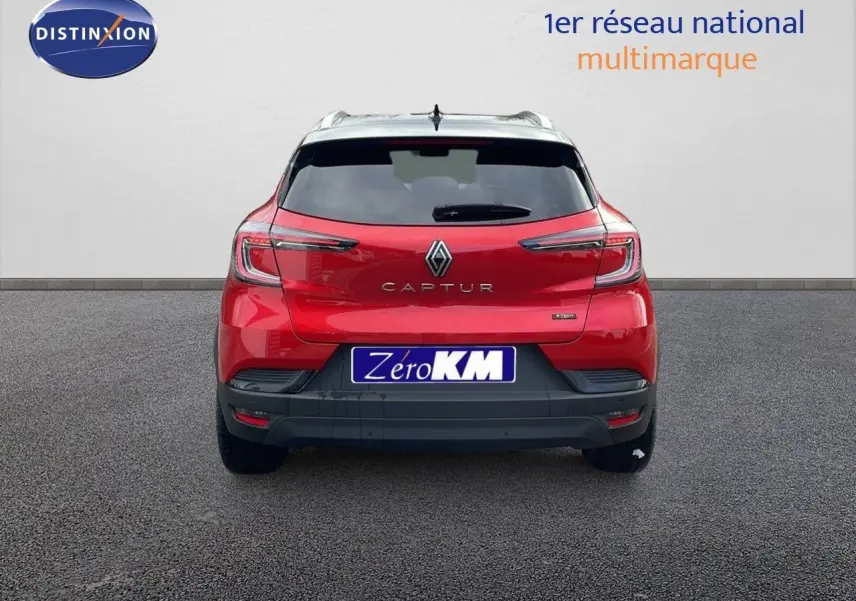 Vue arrière d'un Renault Captur E-Tech hybride rouge passion avec toit noir et plaque Zéro KM visible.