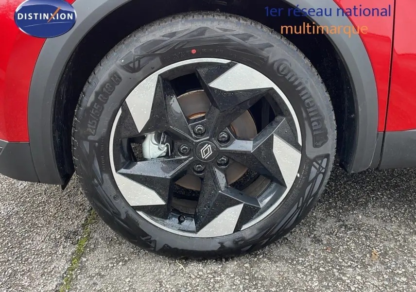 Gros plan sur la roue avant gauche du Renault Captur rouge passion avec jante noire et argentée au design moderne.