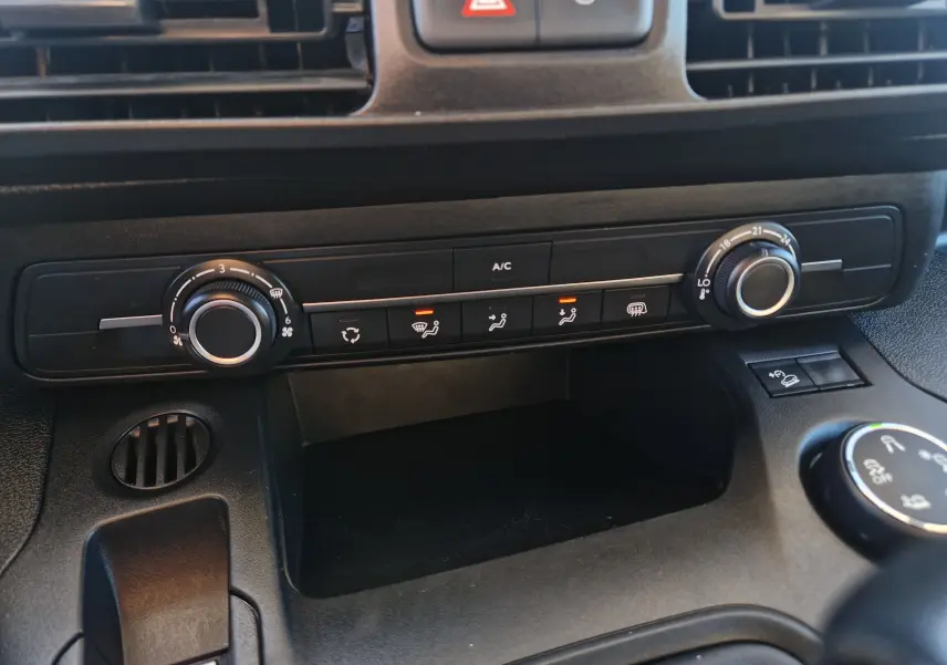 Gros plan sur la console centrale du Peugeot Partner blanc 2021, montrant les commandes de climatisation et ventilation.