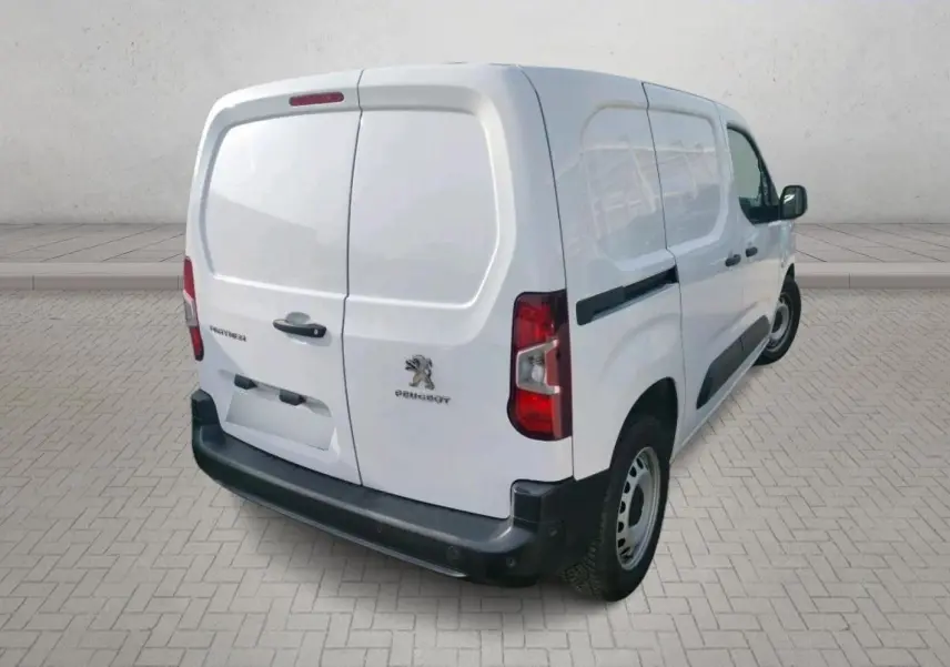 Vue de profil côté gauche d’un utilitaire Peugeot Partner blanc 2021 avec porte latérale pleine et jantes acier.