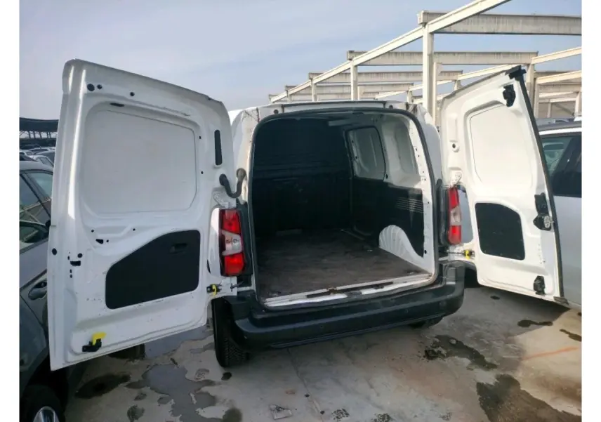 Vue arrière ouverte du Peugeot Partner blanc 2021, montrant l'espace de chargement vide avec plancher en bois et parois noires.