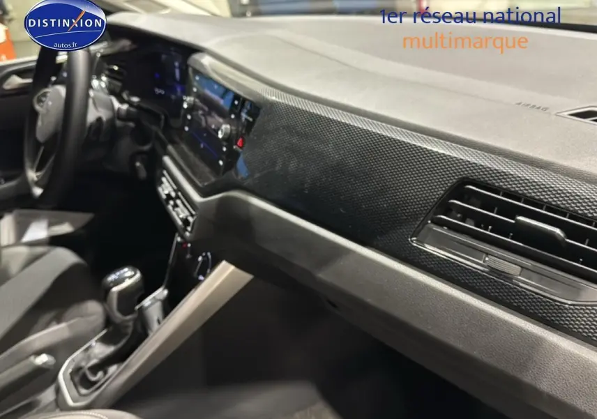 Vue intérieure côté passager de la Volkswagen Polo gris cendre, avec tableau de bord décor lava stone black et console centrale.