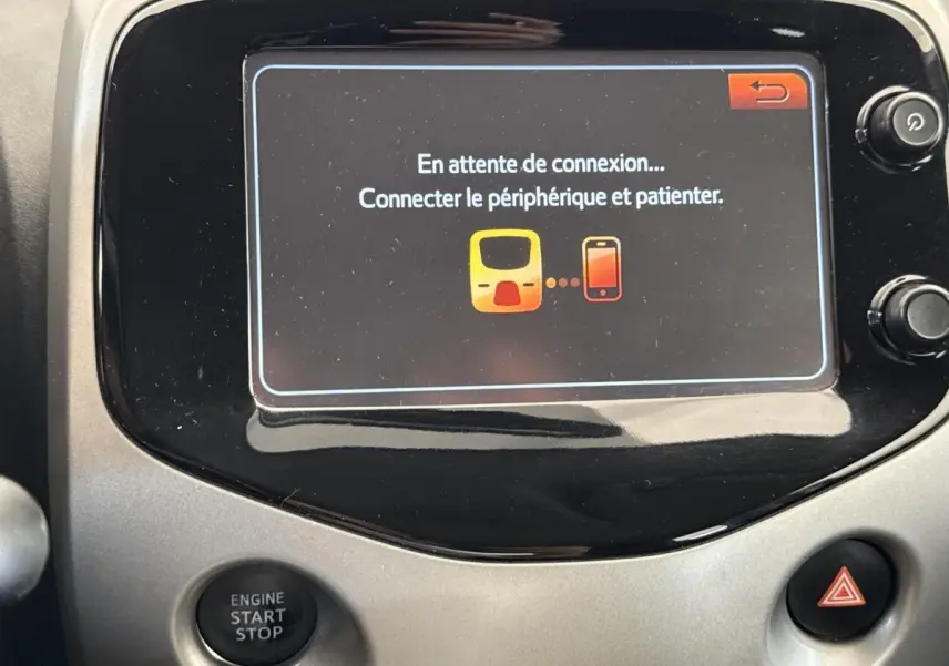 Écran tactile central affichant un message de connexion dans l’habitacle d’une Toyota Aygo gris clair.