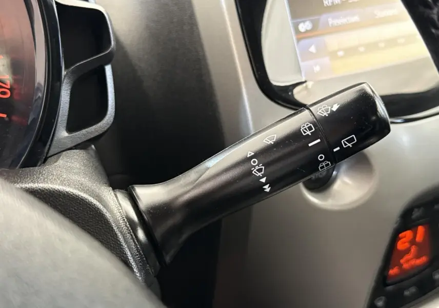 Gros plan sur la commande d’essuie-glaces à gauche du volant dans l’habitacle d’une Toyota Aygo gris clair de 2017.
