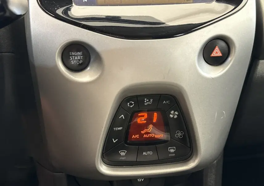 Vue rapprochée de la console centrale grise claire de la Toyota Aygo 2017, avec bouton de warning rouge visible.