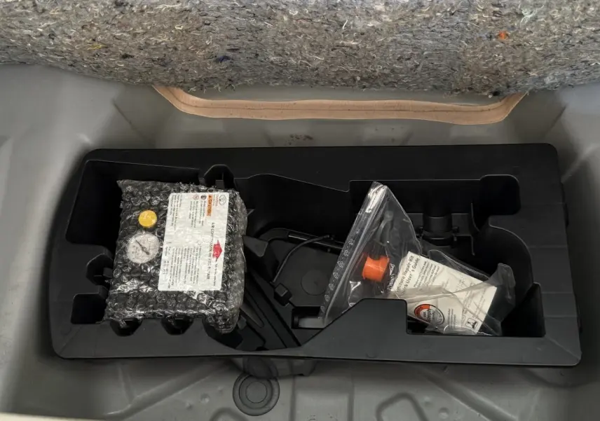 Vue plongeante sur le compartiment de rangement sous la moquette grise d'une Toyota Aygo gris clair de 2017.
