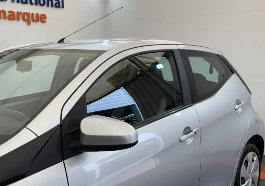 Vue latérale droite d'une Toyota Aygo gris clair 2017 avec rétroviseur assorti et poignées de porte visibles.