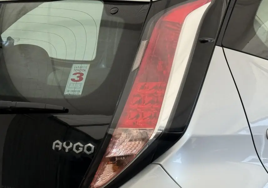 Gros plan sur l'arrière droit gris clair d'une Toyota Aygo 2017, mettant en valeur le feu arrière vertical et le logo AYGO.