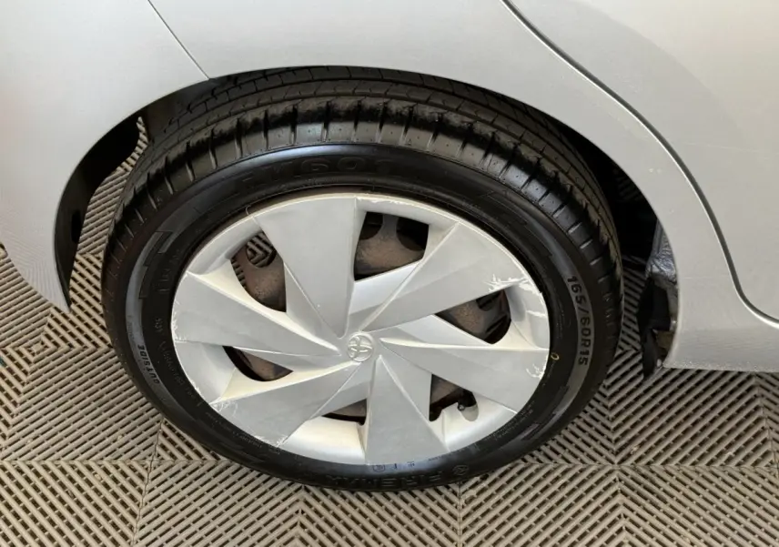Gros plan sur la roue avant droite d'une Toyota Aygo gris clair, avec enjoliveur au design géométrique.