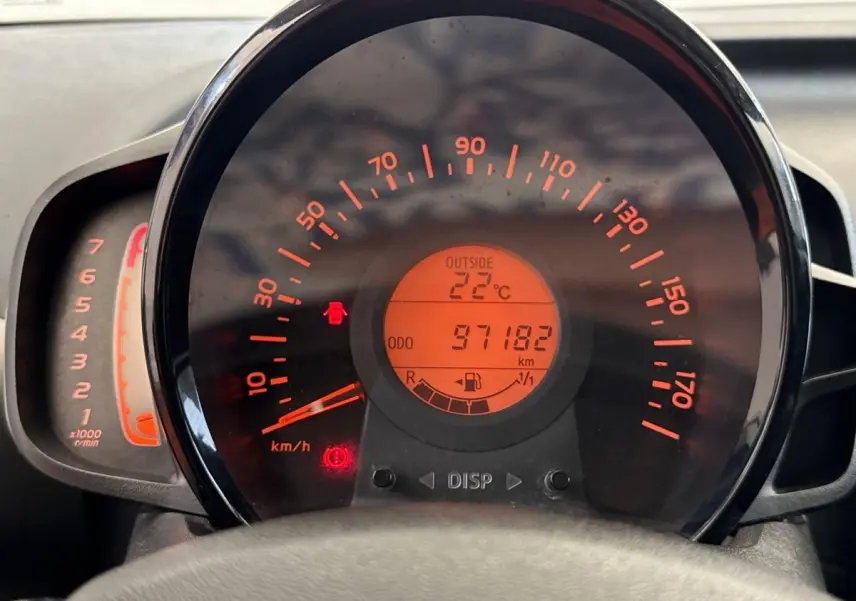 Vue rapprochée du tableau de bord de la Toyota Aygo gris clair, affichant la vitesse, la température extérieure et le compteur kilométrique.