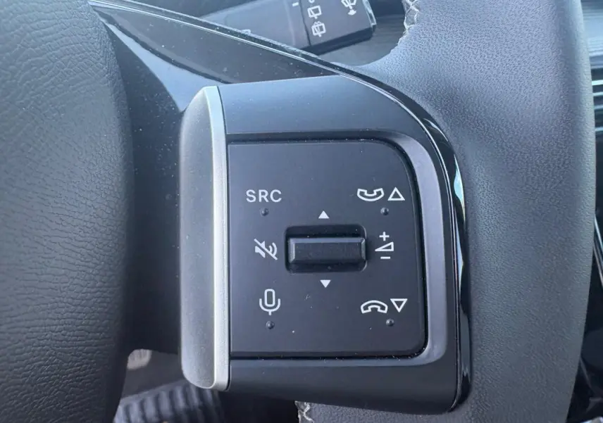 Gros plan sur les commandes vocales et audio au volant du Citroën C3 gris foncé 2025, version Turbo 100 ch Manuelle Max.